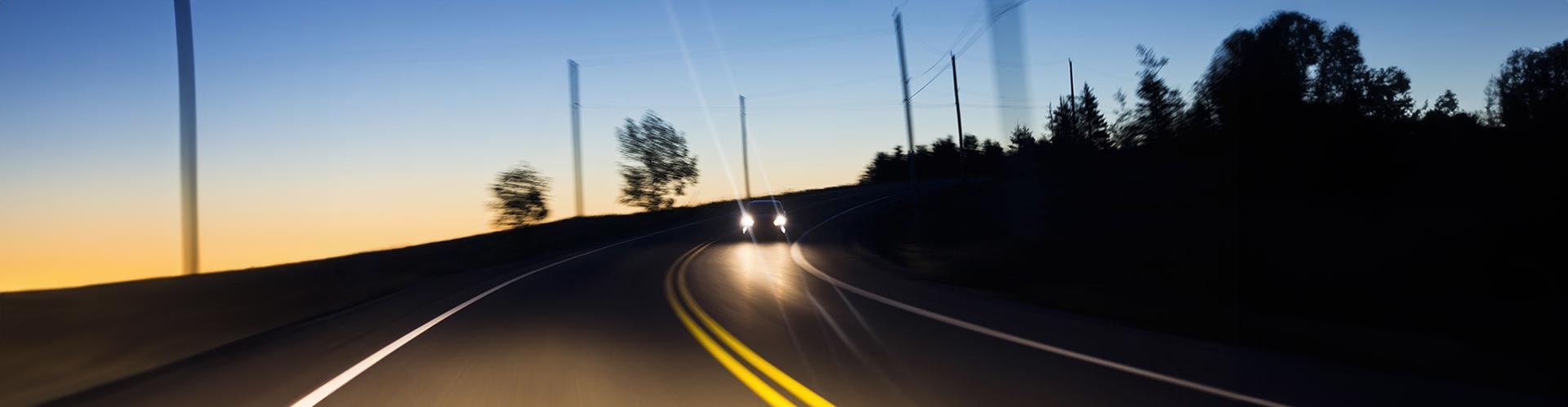 A pair of headlights on a car flash in warning to an approaching driver