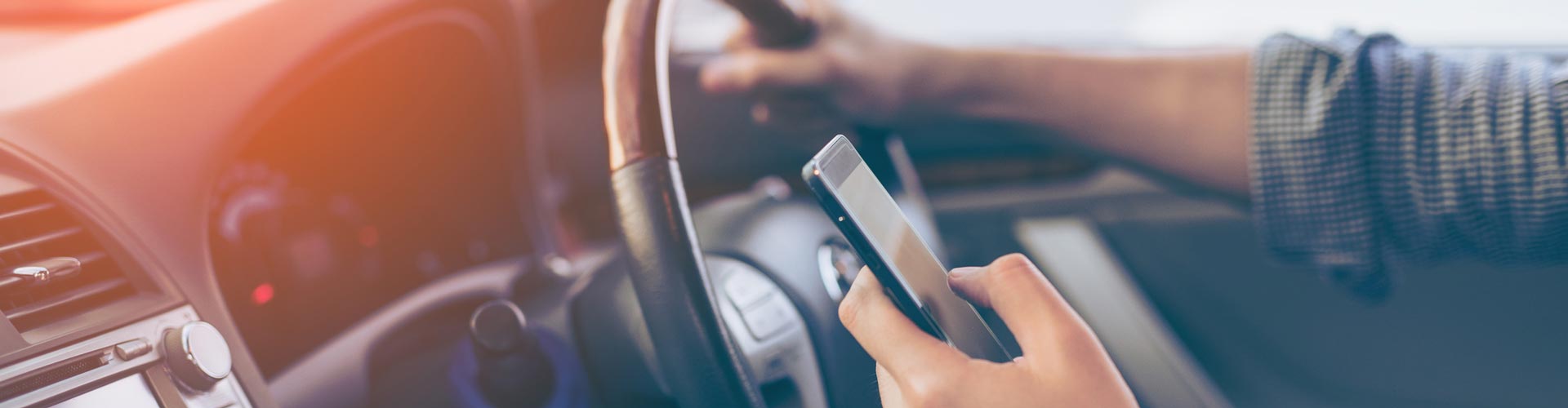 A driver's hand holds a mobile phone
