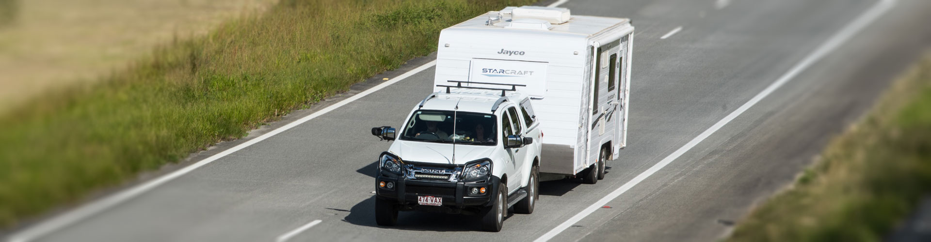 Isuzu SUV towing a white caravan on an open road seen from above