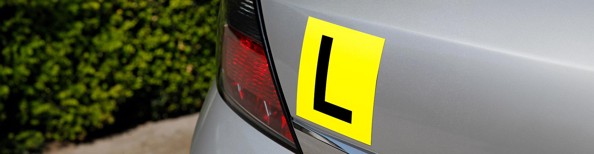 Yellow learner driver's plate on the rear of a silver car