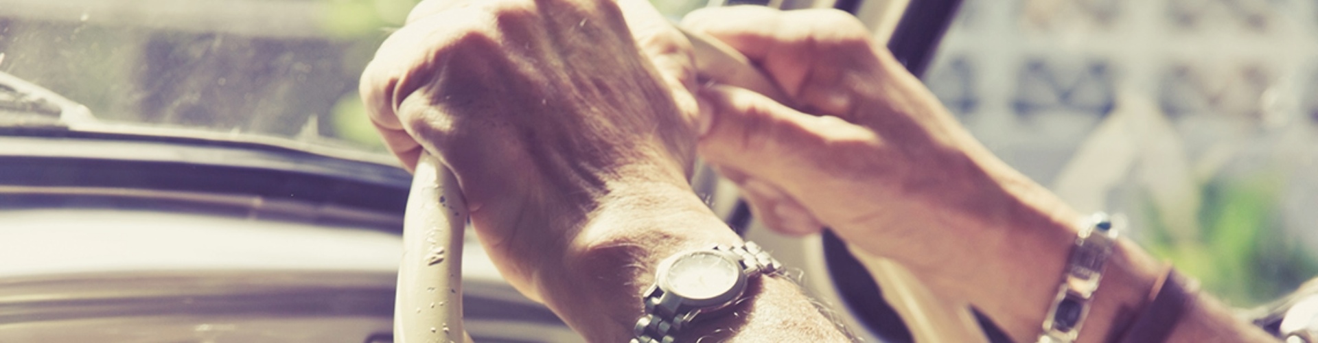 Senior driver steering wheel close up of a man's hands and arms and steering wheel of a classic vehicle