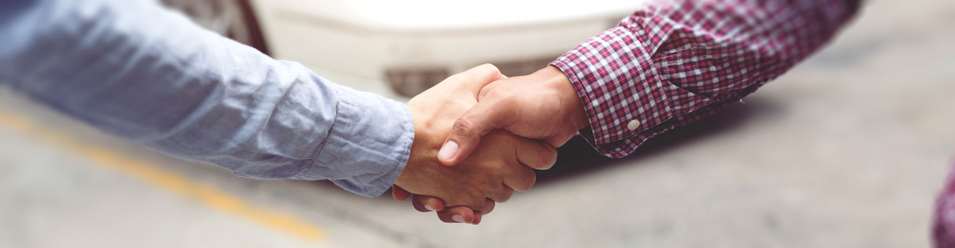 Closeup of two hands shaking, with one clad in red flannel, and a blurred background