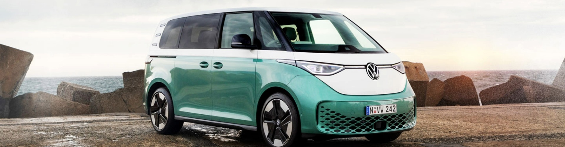 Angled side view of a green VW ID Buzz parked on a mountainside dirt road.
