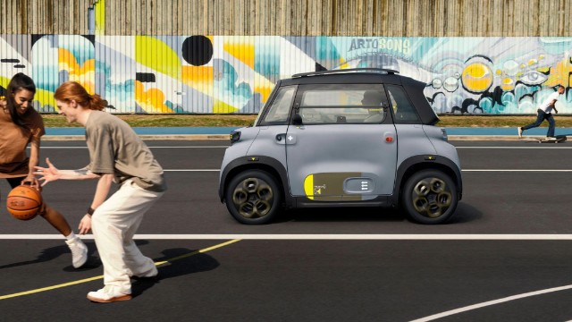 Two young people play basketball in front of a Citroen Ami micro-ev