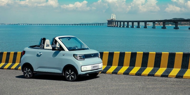 A Wuling Mini micro-ev sits parked beside the sea