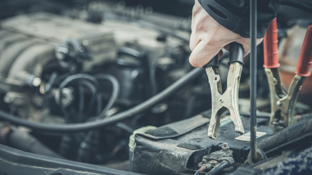 Close-up of jumper leads being attached to a car battery