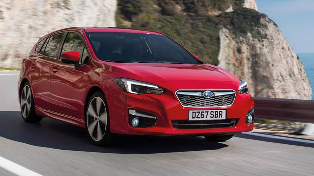 Red Subaru Impreza driving on coastal road with cliff in background