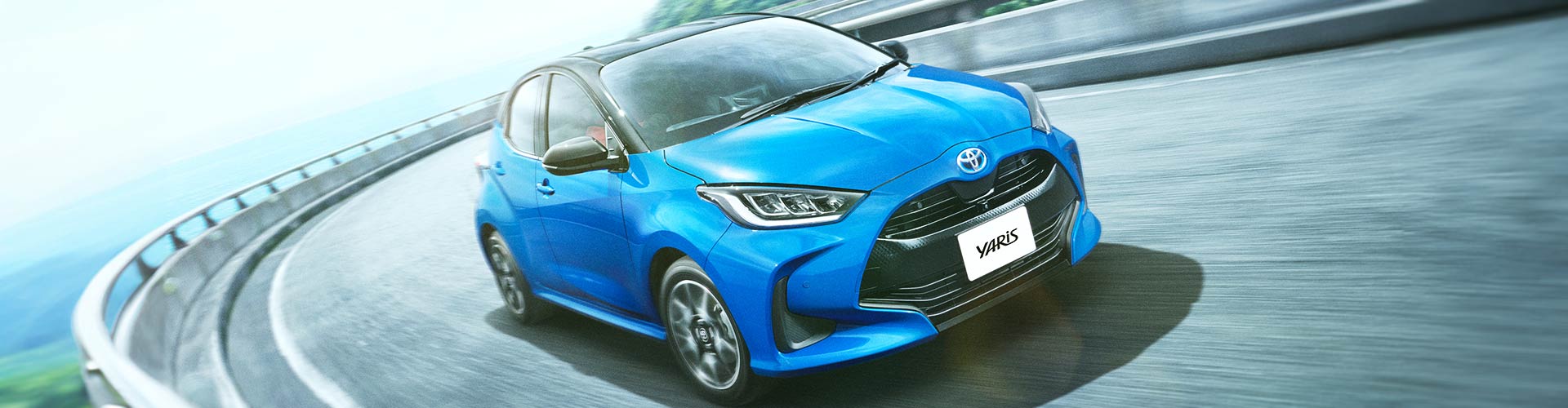 Grainy image of a blue 2020 Toyota Yaris driving on a curvy road