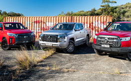 Three utes parked in front of rusty wall
