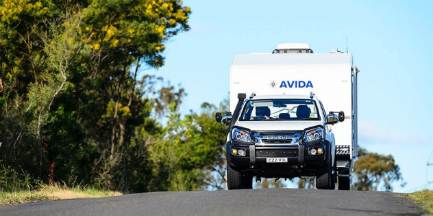 Front view of an SUV towing a caravan down a country road