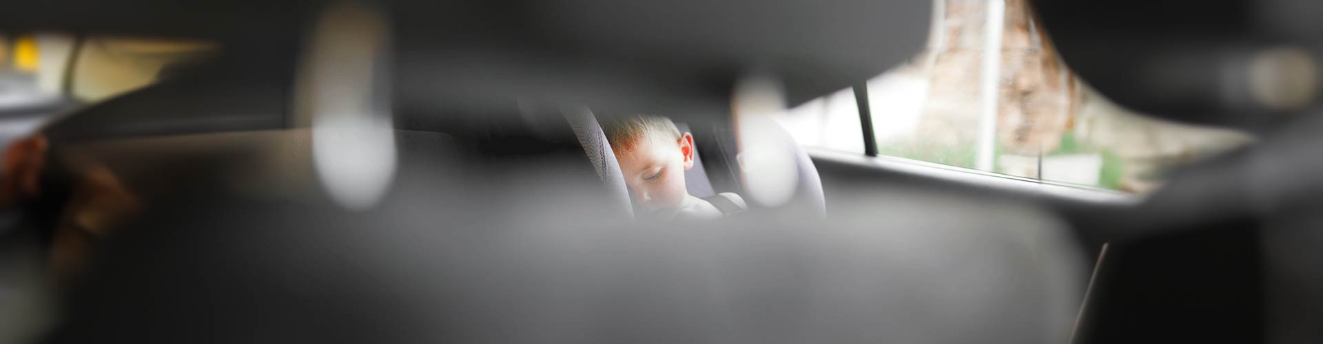 Child sleeping in car seen from a blurred foreground of front row seats