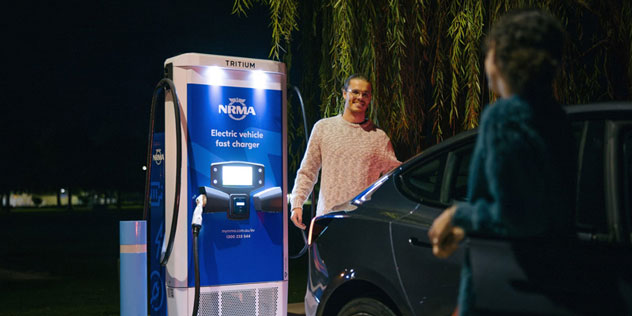 Couple charging an EV at an NRMA charger at night