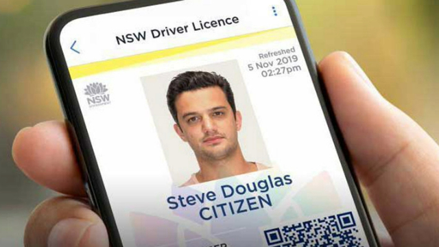 Close-up of a hand holding a phone displaying a digital driver licence name and image of a man