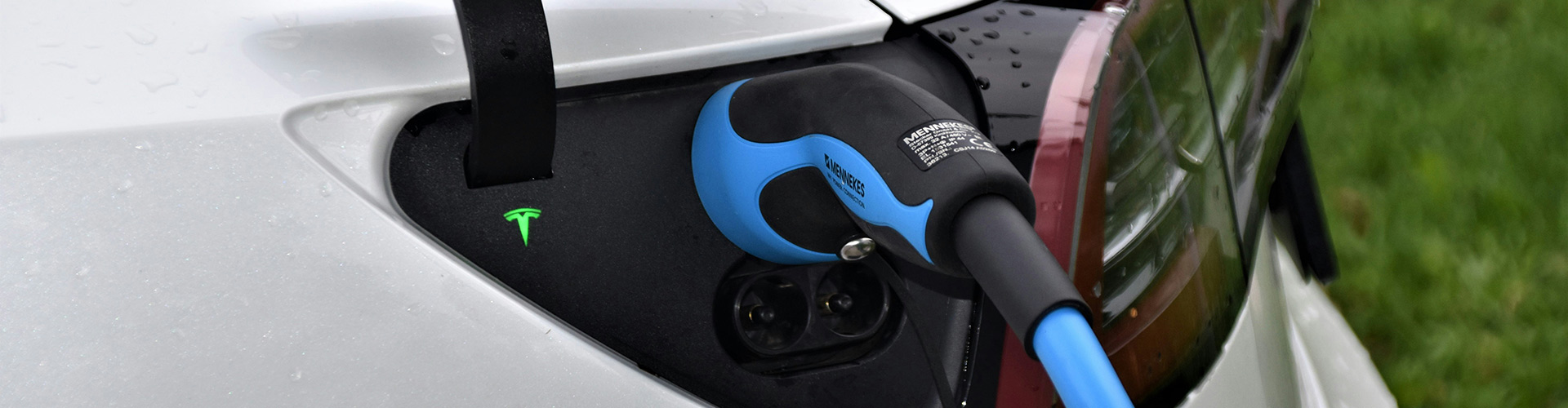 Blue electric charging cable charging a white electric vehicle