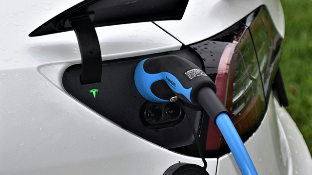 Blue electric charging cable charging a white electric vehicle