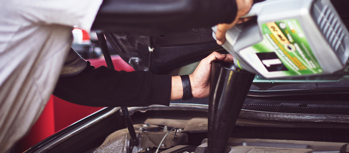 Engine oil top up Side view of a driver topping up a car engine with motor oil