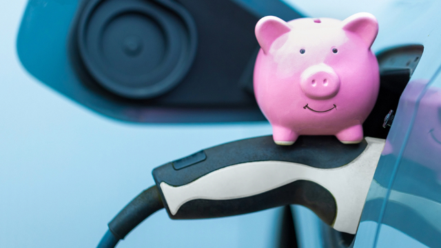 A pink piggy-bank sits on an EV's charging plug 