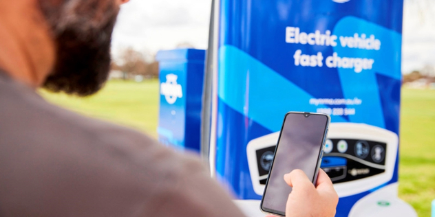 man looking at mobile phone at NRMA EV fast charging station