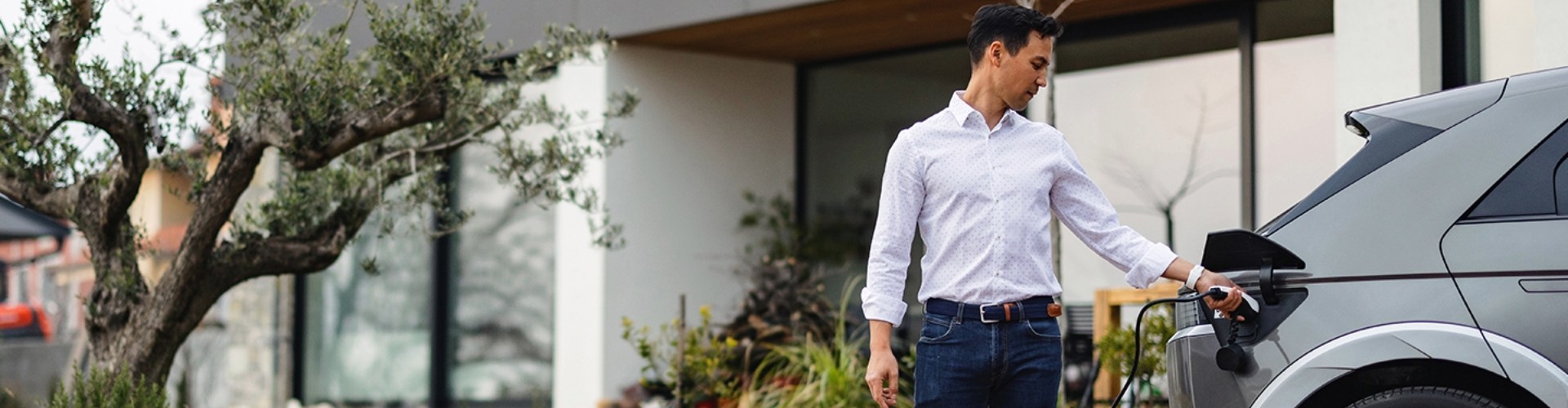 A person plugs their EV in to charge in their driveway