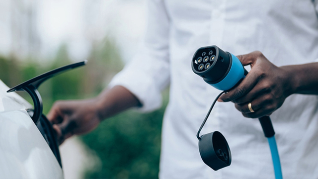 A man plugs the charging cable into an electric vehicle