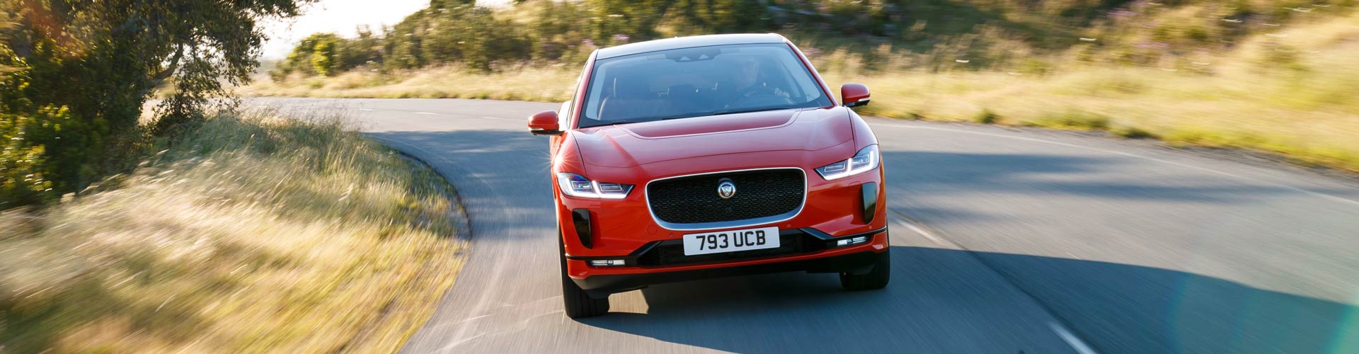 Red 2019 Jaguar I-Pace driving towards viewer on road