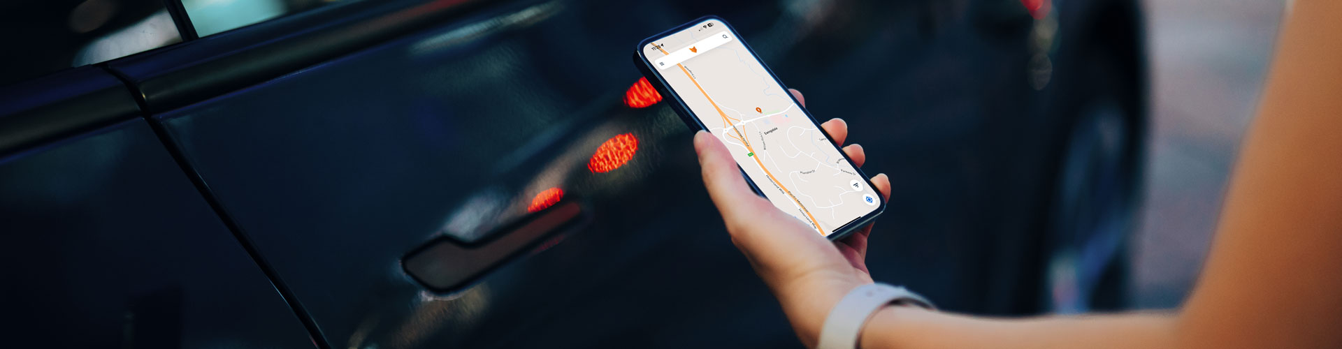 A hand holding a phone in front of a car door