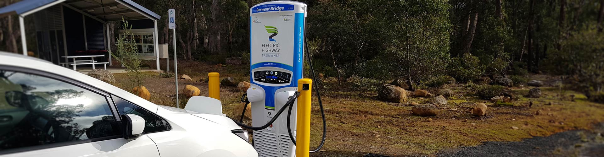 A white EV plugged into an EV charger in a bush setting at Derwent Bridge Tasmania