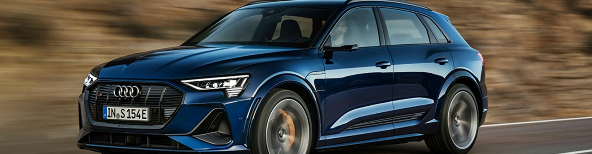 Side view of a blue 2021 Audio e-tron S travelling on a road.