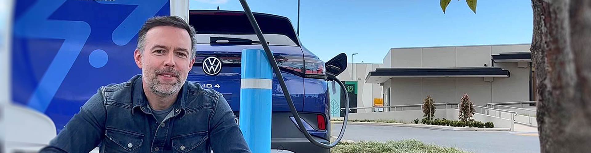 A man and VW ID4 electric car parked in front a NRMA fast charger