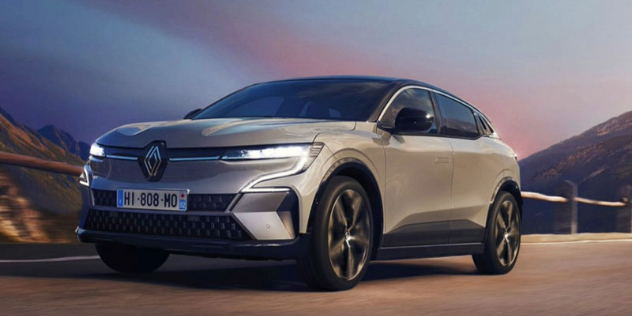 Front view of a Renault Megane E-Tech driving up a mountainside pass at dusk.