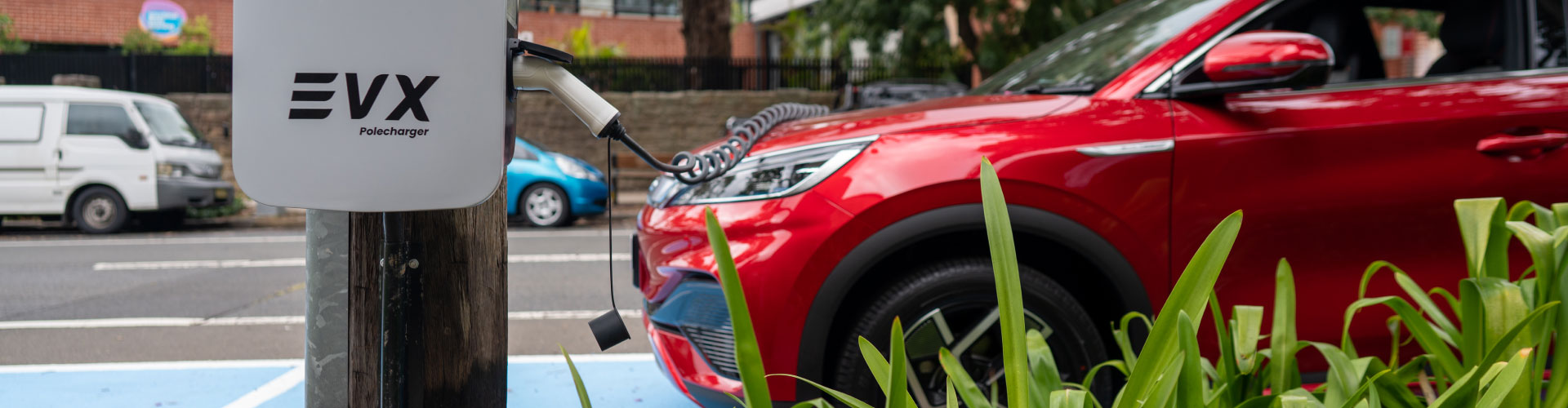 A red EV charging on the street
