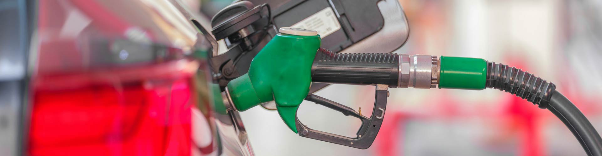 A closeup of a green petrol bowser inserted into a car