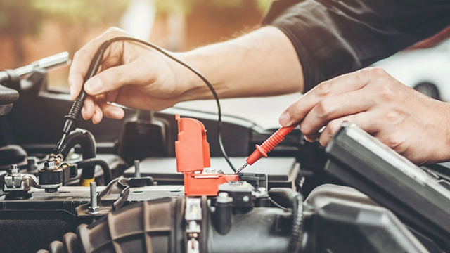 Close-up of a technician's hands assessing a car battery