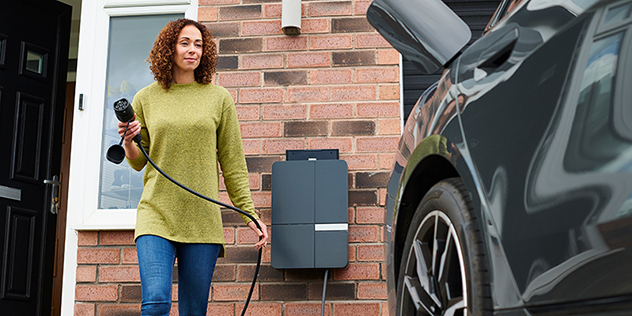 Female home owner charging electric car in driveway