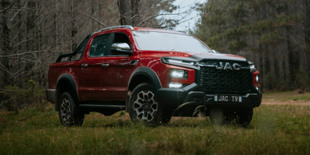 JAC T9 dual-cab ute side-angle view parked in forest terrain.