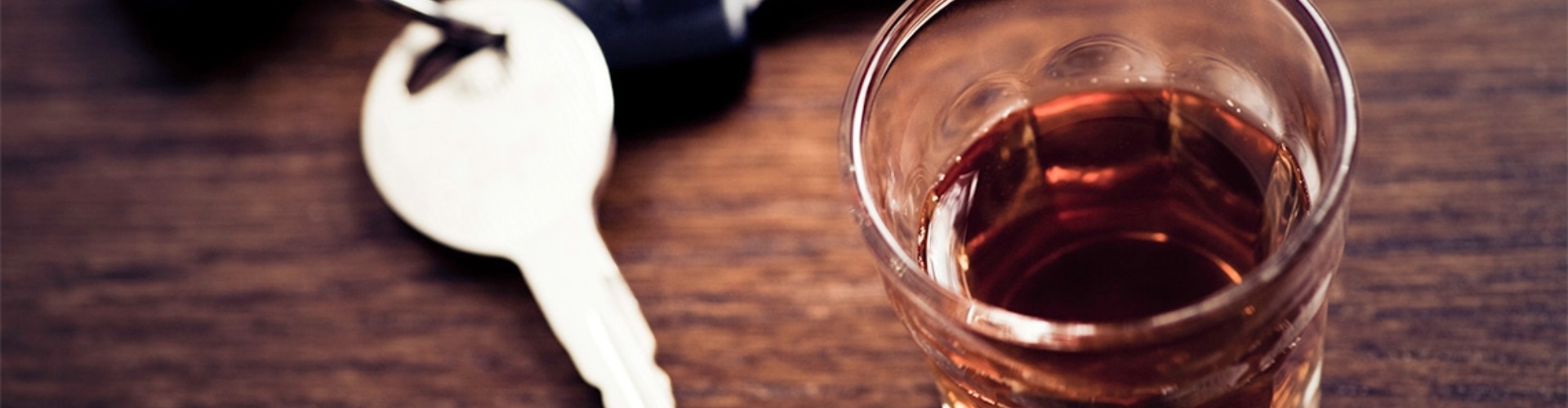 An alcoholic drink sits beside car keys