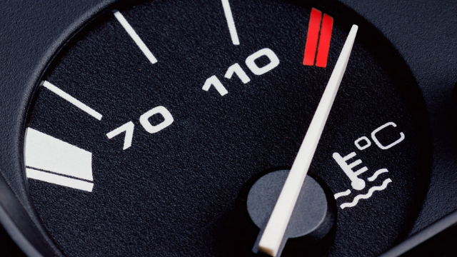 Close-up view of an overheating car dashboard temperature gauge
