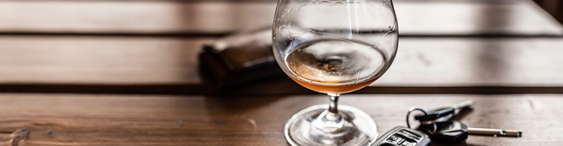 A key fob sits on a table beside a glass of alcohol