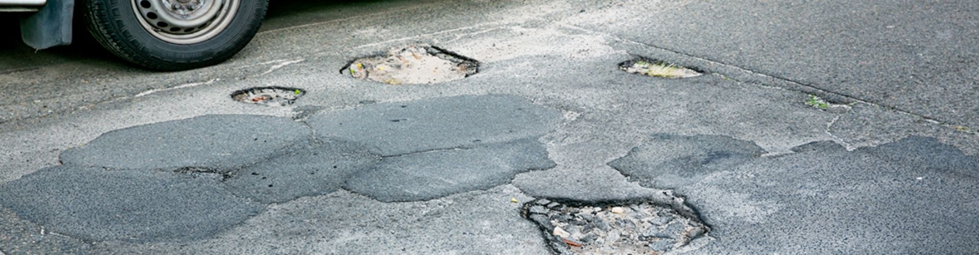 A bus parked on an asphalt road in bad condition