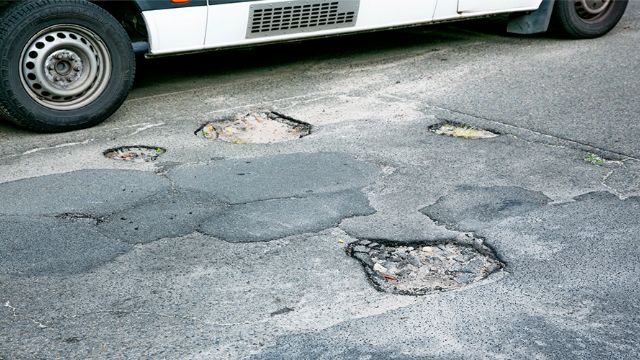 A bus parked on an asphalt road in bad condition