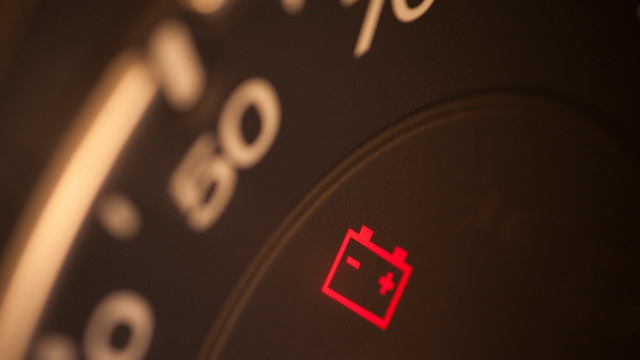 Close-up of a car's dashboard with the battery icon lit