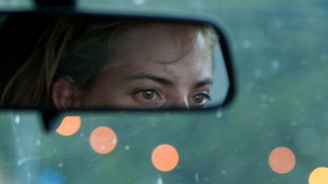 Reflection of the top half of a woman's face in the car review mirror. 