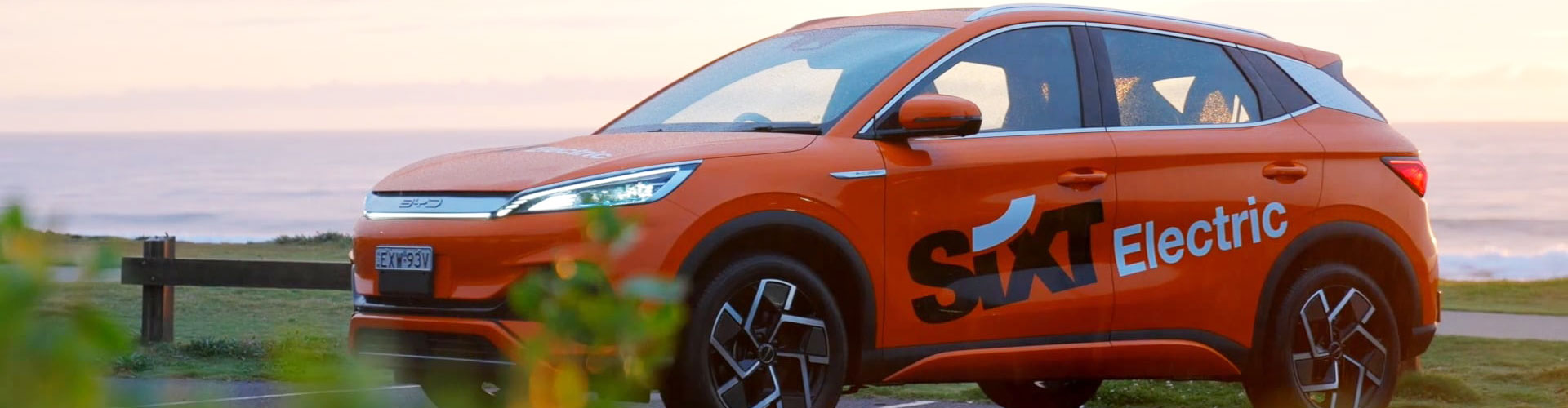 An orange SIXT BYD Atto 3 near the beach