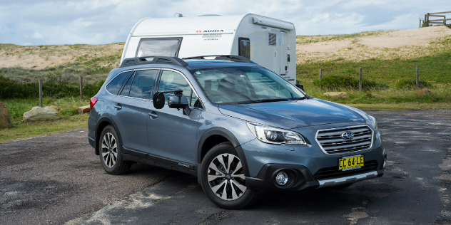 Front view of a stationary Subaru Outback towing a caravan