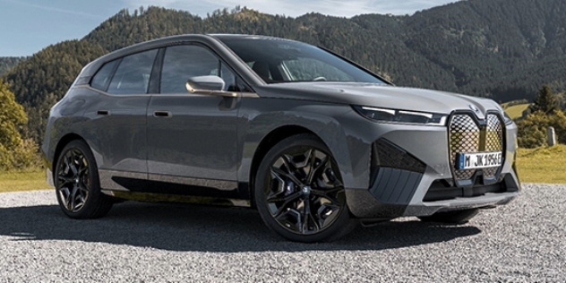 A BMW iX xDrive50 Sport sits parked amongst a mountain range