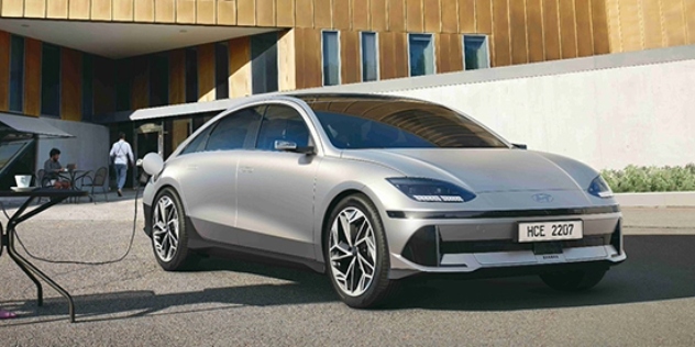 A woman sits outside with her laptop plugged into a Hyundai Ioniq 6 Dynamiq