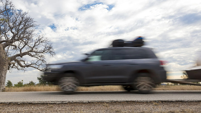 Side view of an SUV towing a caravan along an outback road
