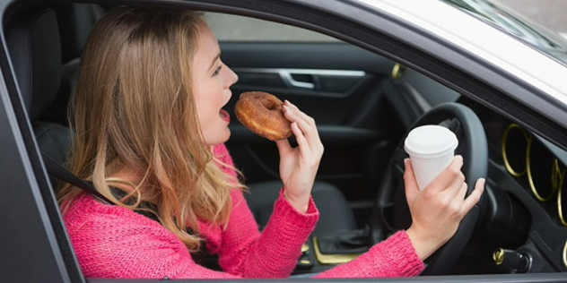 Woman eating a donut while driving