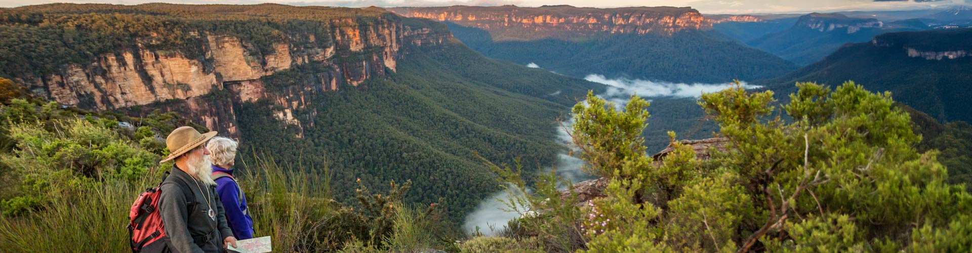 Older couple pause hiking to view Blue Mountains vista