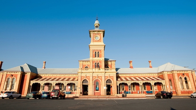 view of the front of red brick and sandstone historic railway station with clock and bell tower